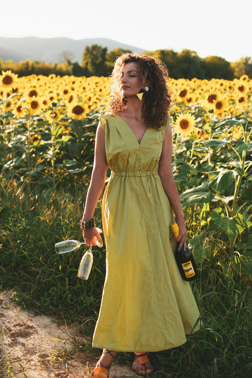 Woman in a yellow sleeveless summer dress standing in a wildflower field — placeholder image